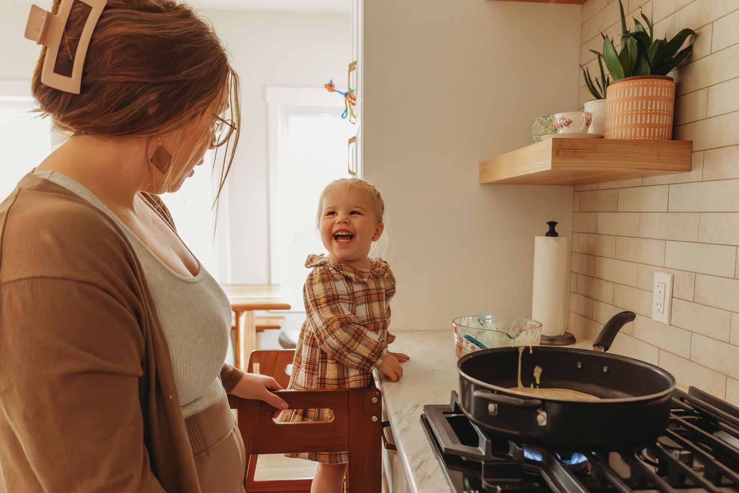 Cooking together in modern kitchen with child standing on learning tower.