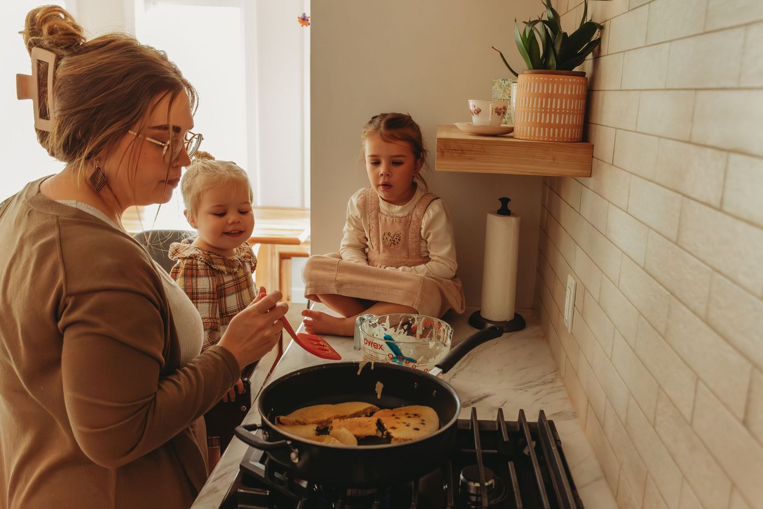 Family cooking together in a bright kitchen while making homemade soup on the stovetop.