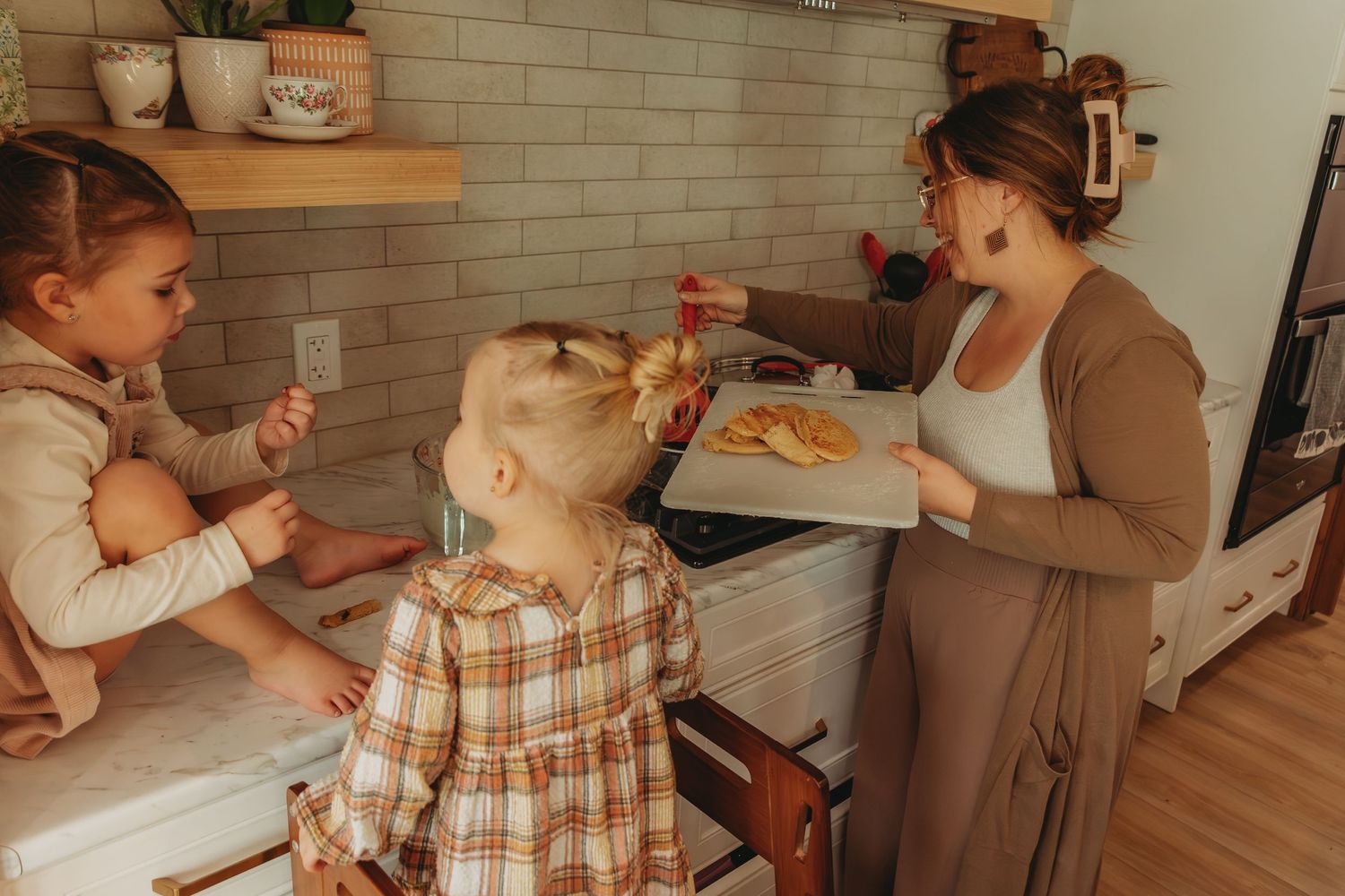 Family enjoying food preparation together in warmly lit kitchen with subway tile backsplash.