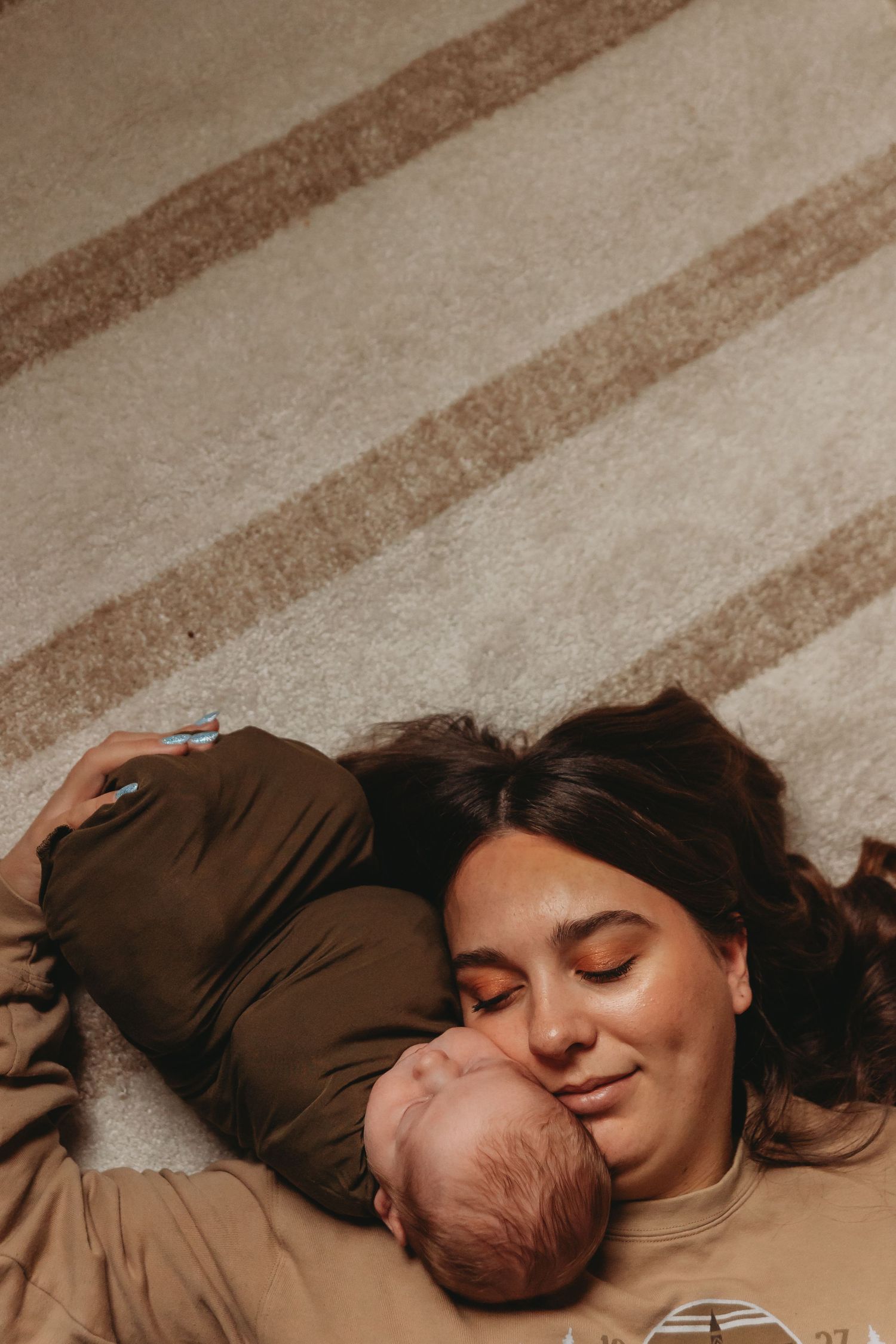 Intimate portrait on striped carpet showing quiet moment with newborn.