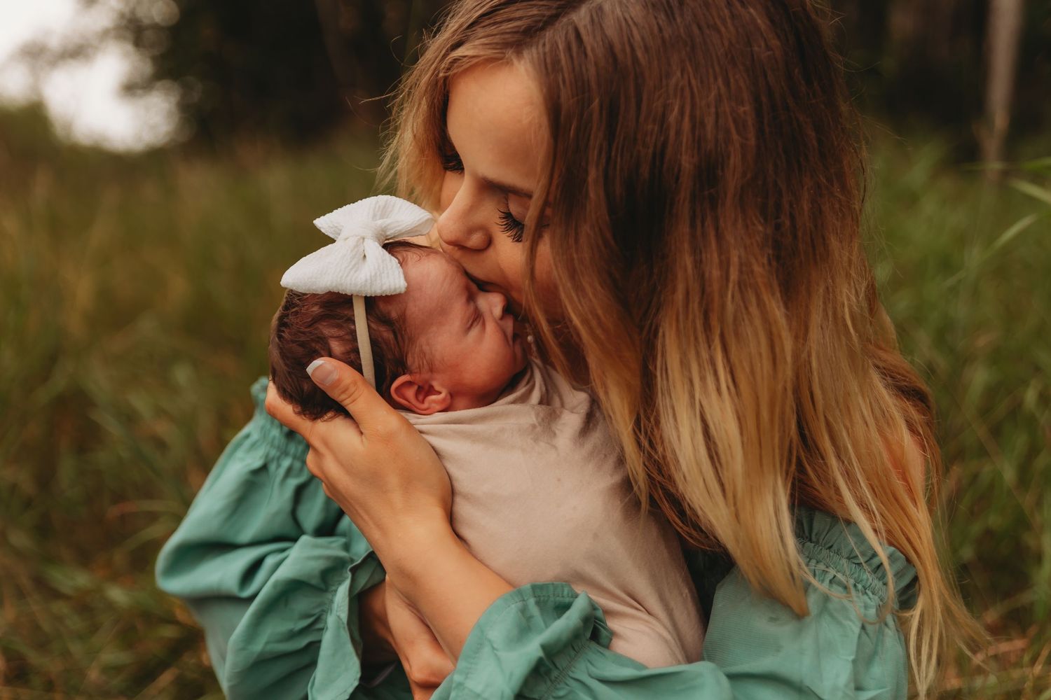 Tender moment between parent and baby outdoors in natural lighting.