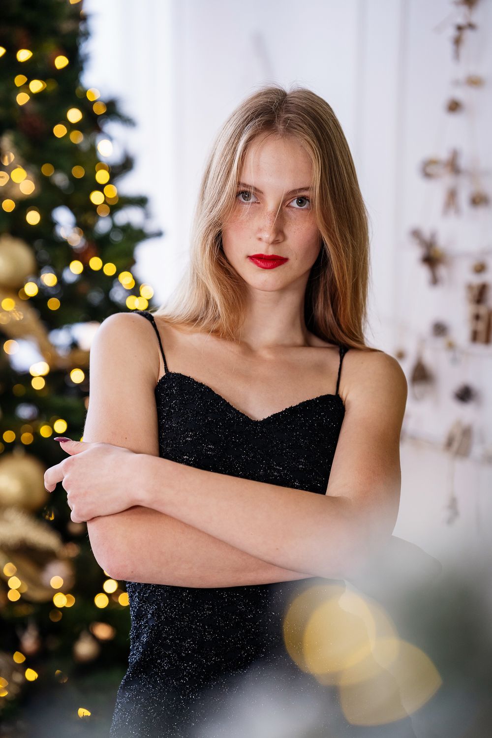 Sophisticated portrait with Christmas tree and decorative lights in background.