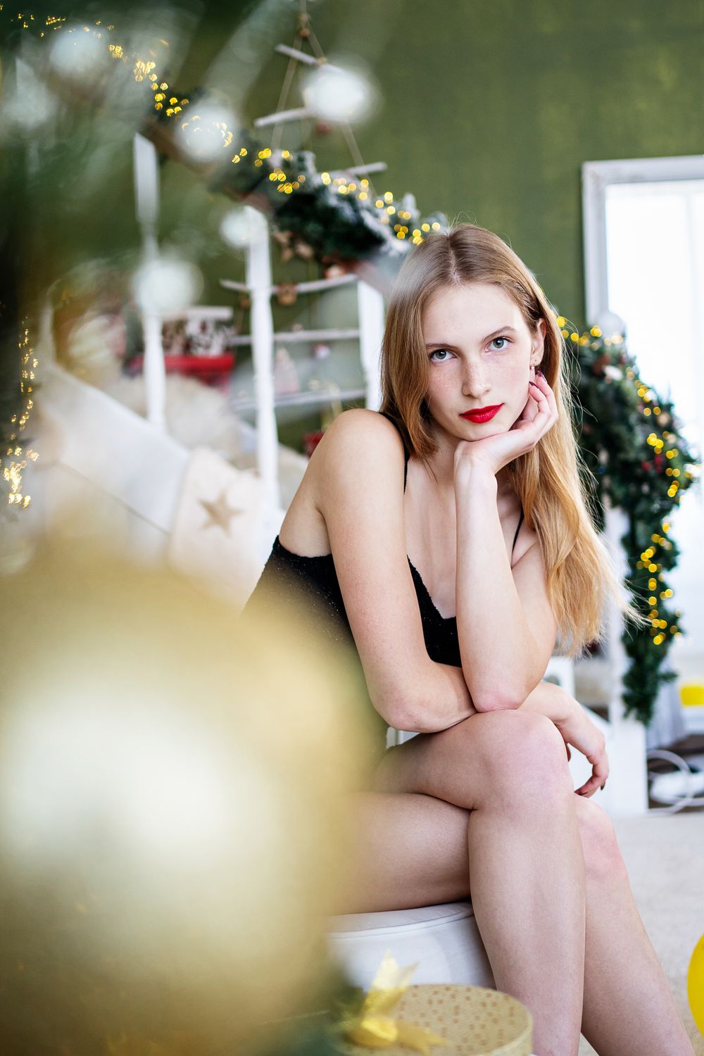 Dreamy Christmas portrait with soft focus ornaments and twinkling lights.