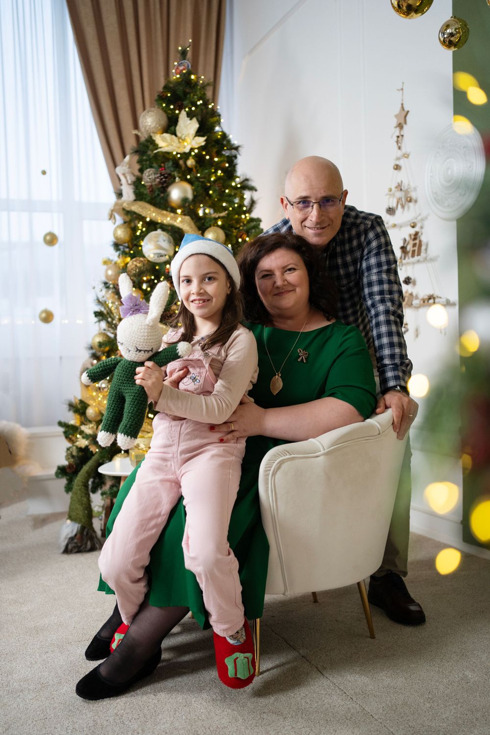 Festive family portrait in front of decorated Christmas tree with gold ornaments.