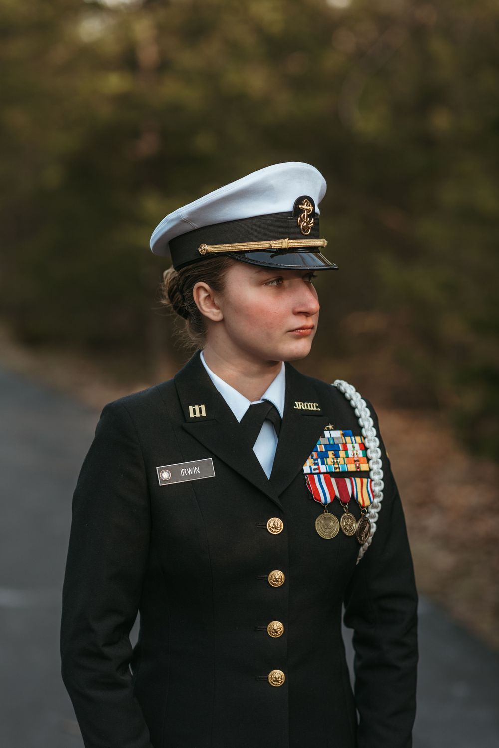 A decorated military officer in dress uniform with medals and captain's hat stands in a formal pose.