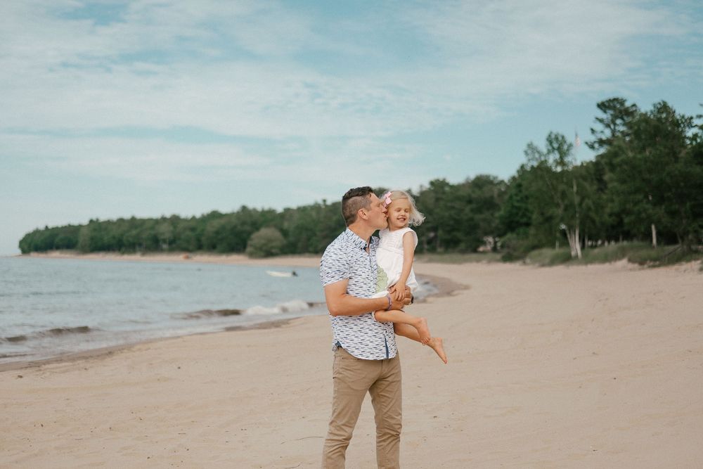 A loving pair share romantic moments along a scenic sandy beach, laughing and embracing by the shoreline.