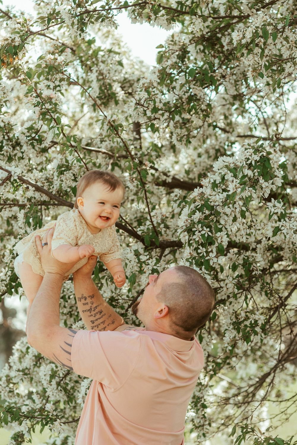 A touching moment captured under blooming spring tree branches with white flowers.