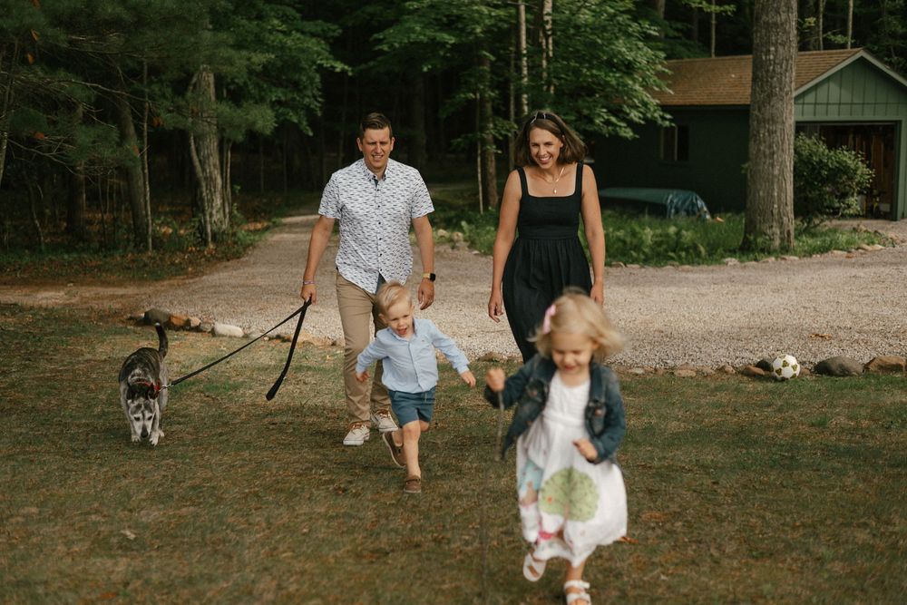 Family and dog playing together outdoors in a wooded area during a summer afternoon.