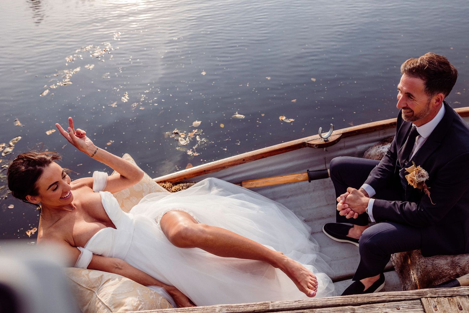 Bride relaxes in boat, groom laughs at Gilpin Hotel, the Lake District
