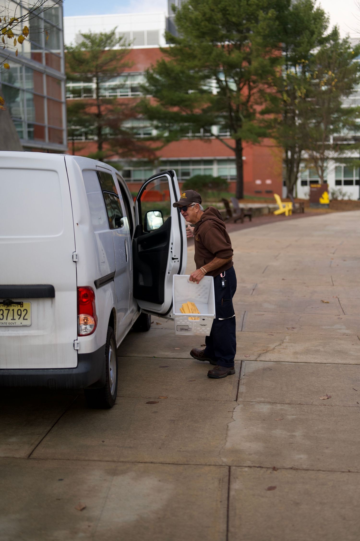 A person checking inside a white university van parked on campus.