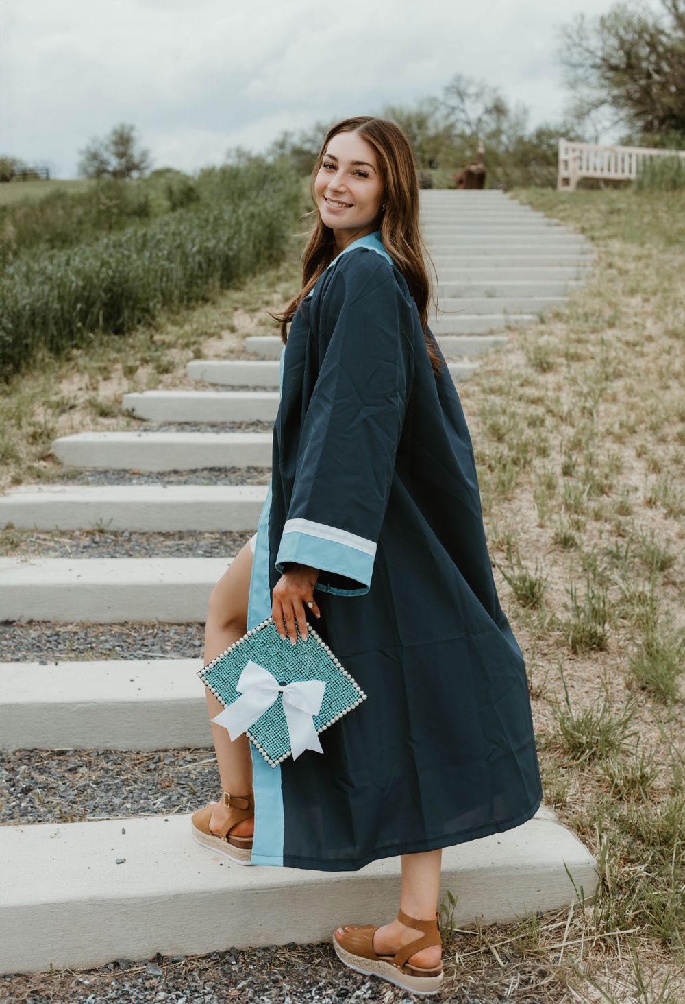Person wearing navy dress twirls on concrete steps outdoors.