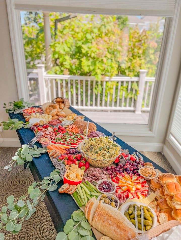 Colorful charcuterie board with meats, cheeses, fruits and vegetables displayed on a sunlit porch.