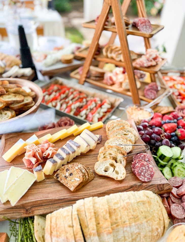 Elaborate charcuterie spread featuring cured meats, cheeses, bread, and fruits on wooden serving boards.