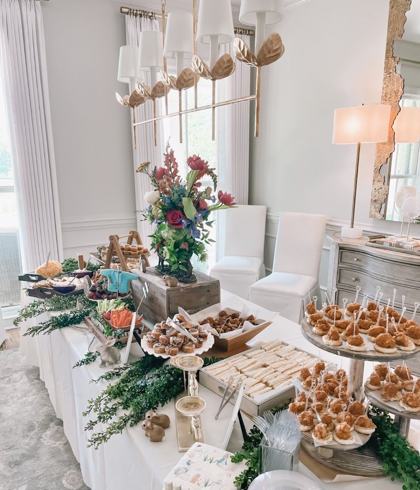 White elegant dessert table with tiered displays of sweet treats and greenery decorations.