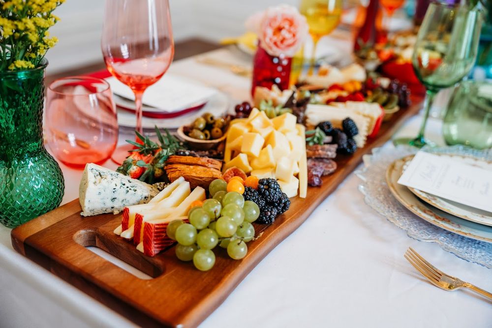 Wooden charcuterie board with colorful fruits, meats and cheeses styled for an elegant event.