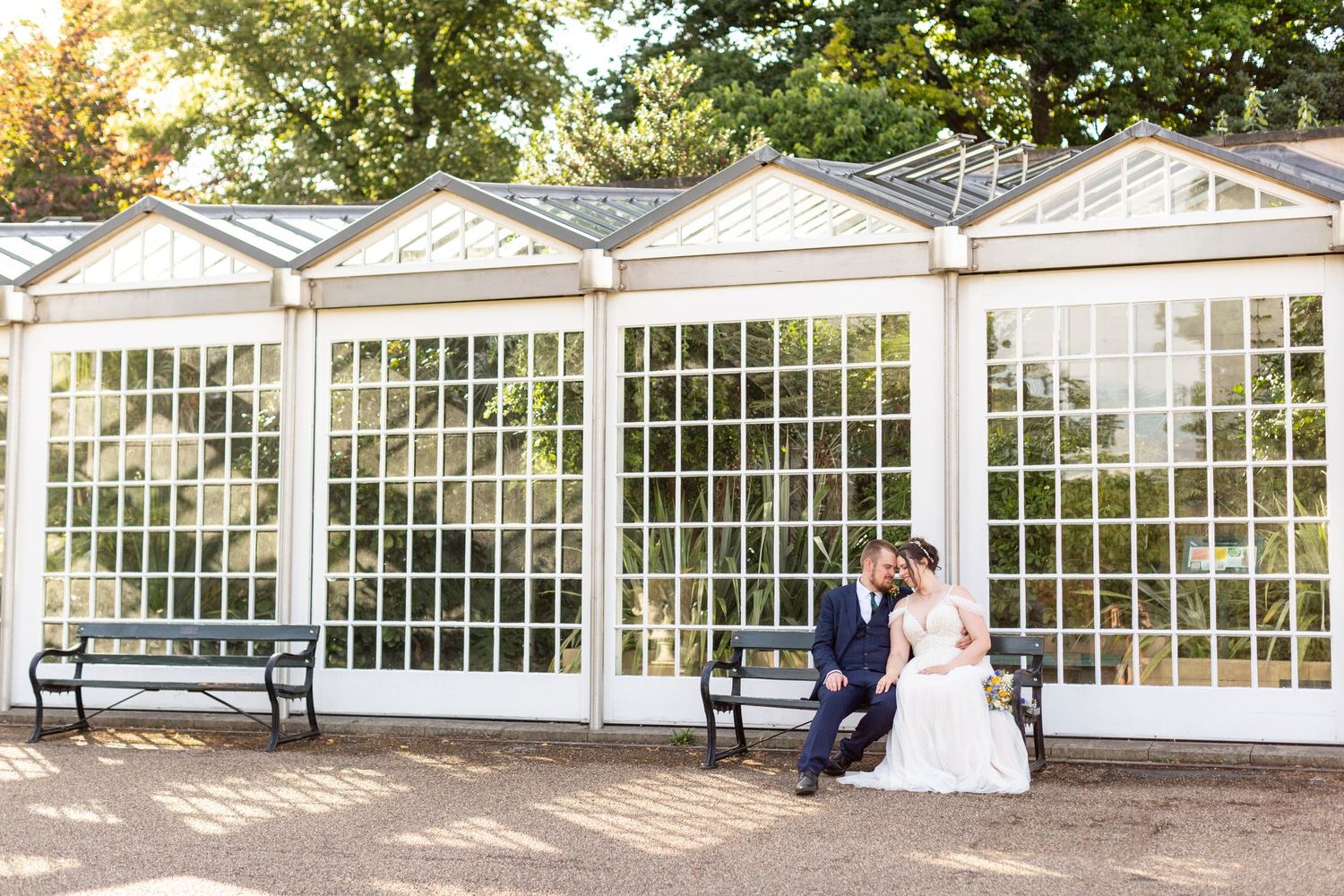 A romantic wedding scene outside a white conservatory with large windows.