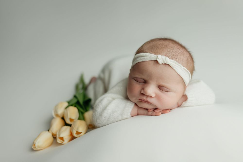 Newborn girl on white background with yellow tulips, taken by Jen Knightstep, Photographer