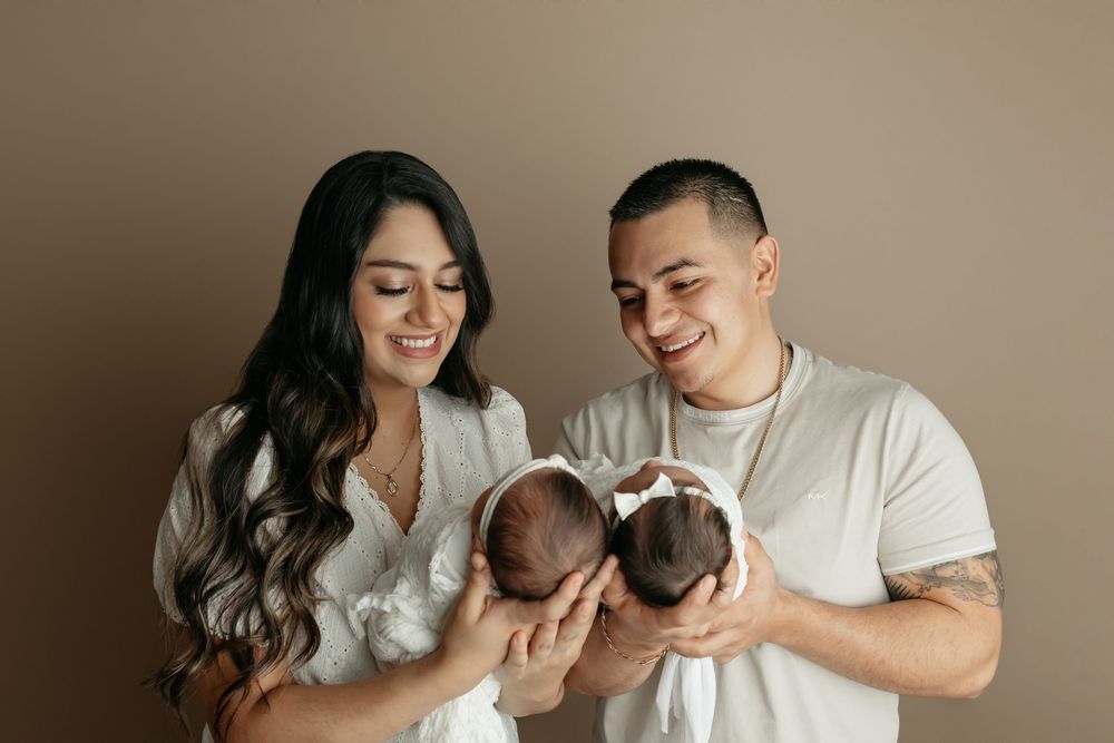 Mama and daddy holding twin newborn girls,  taken by Jen Knightstep, Photographer