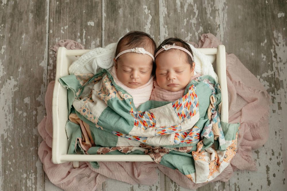 Twin girl newborns in a cradle with a vintage green quilt, taken by Jen Knightstep, Photographer