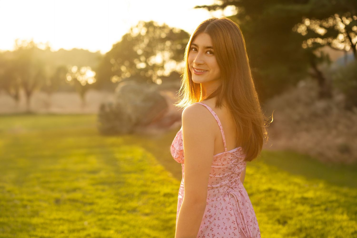 Someone in a yellow top sits among tall golden grass on a sunny afternoon in a scenic outdoor setting.