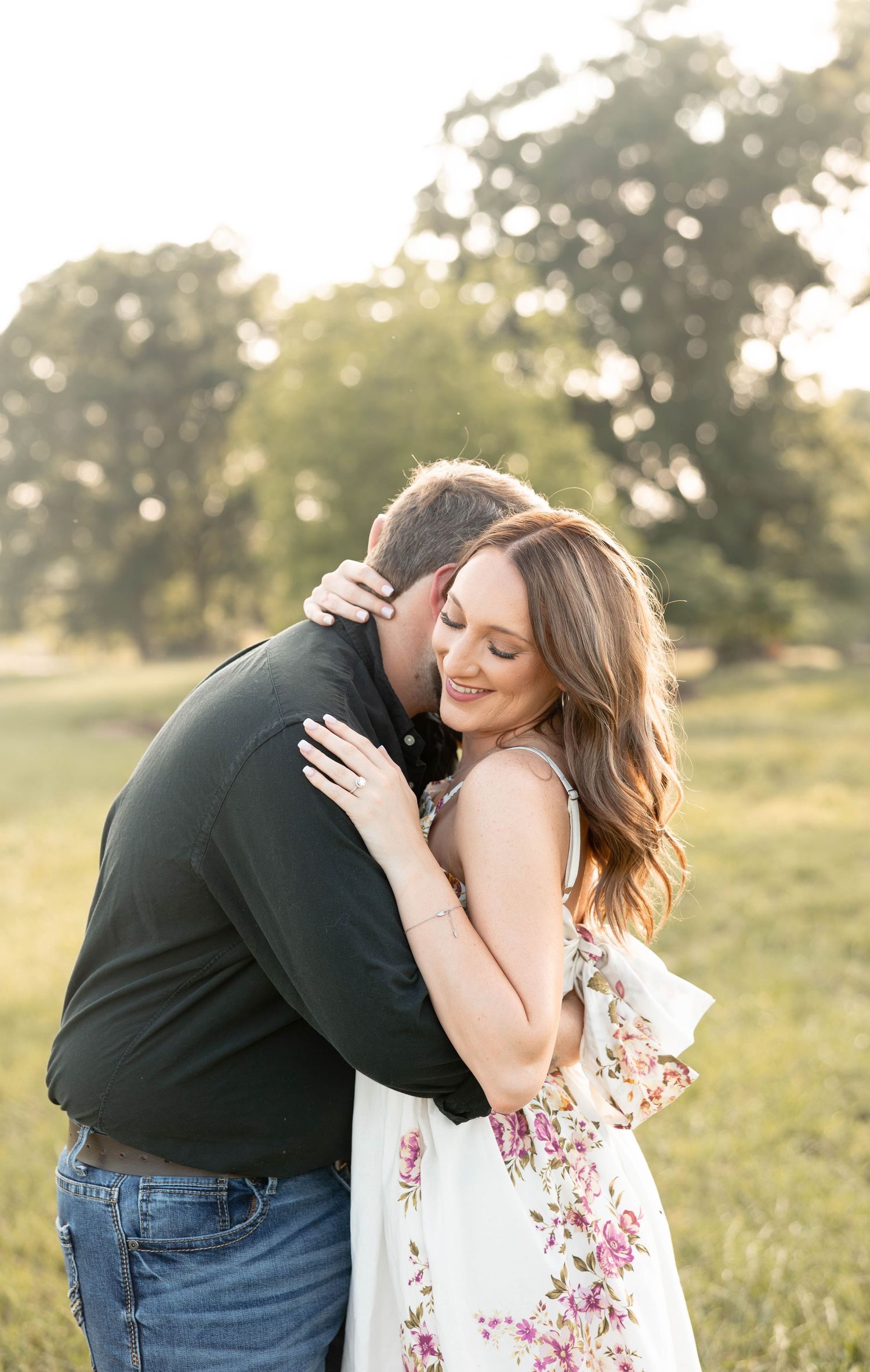 Romantic couple embracing against a white wall, with the woman in white and man in blue plaid.