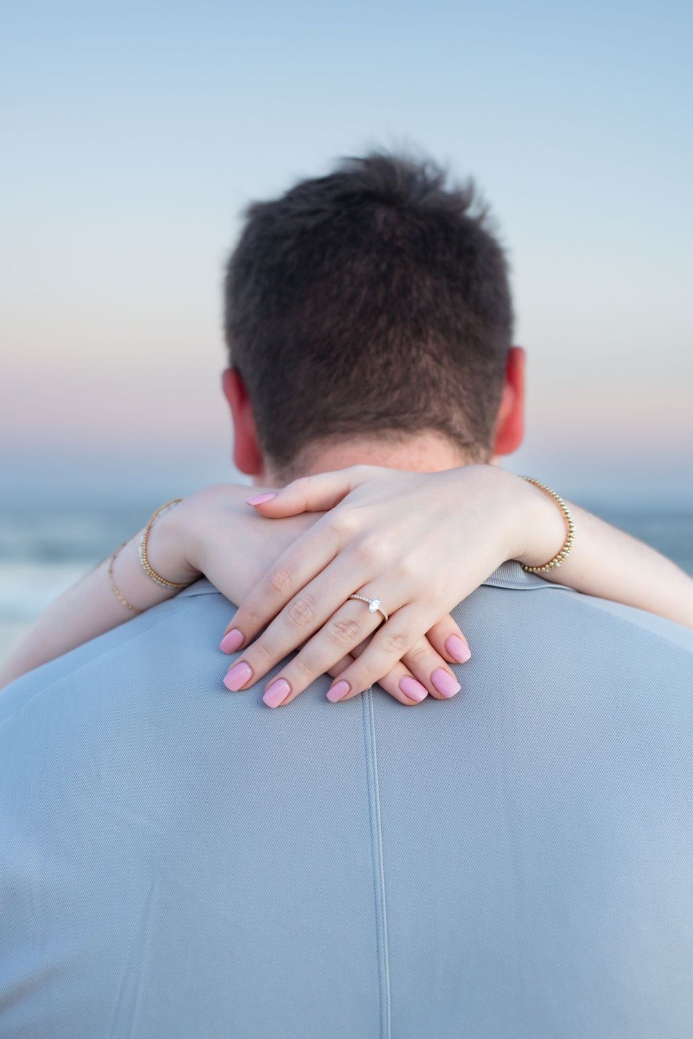 Four progressive photos show hands placed on a light blue fabric surface against a soft sunset background.