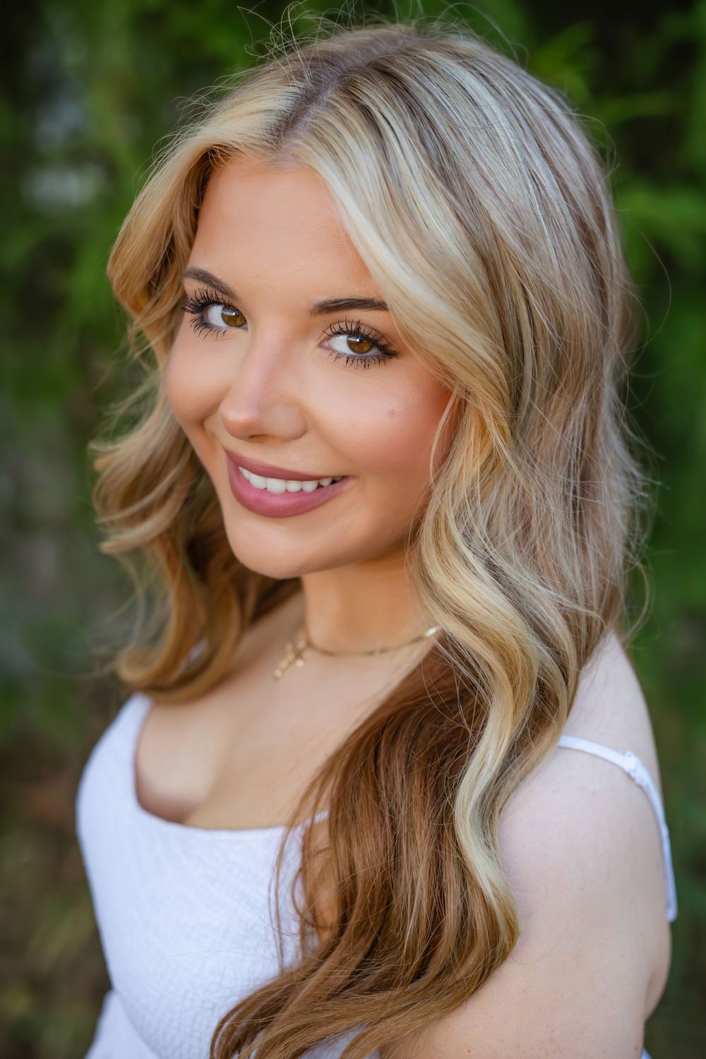 Portrait series showing blonde hair and white top in outdoor natural lighting against green foliage background.
