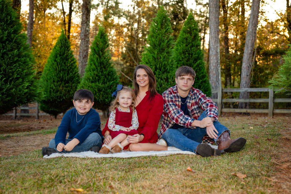 A group lounges together on autumn grass during a casual outdoor photo session at golden hour.