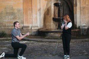Two people share a special moment at an old stone building with archways.