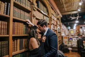 A couple browses books together in a cozy bookstore with wooden shelves and warm lighting.