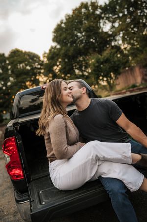 A couple shares an intimate moment while relaxing in the bed of a pickup truck at sunset.