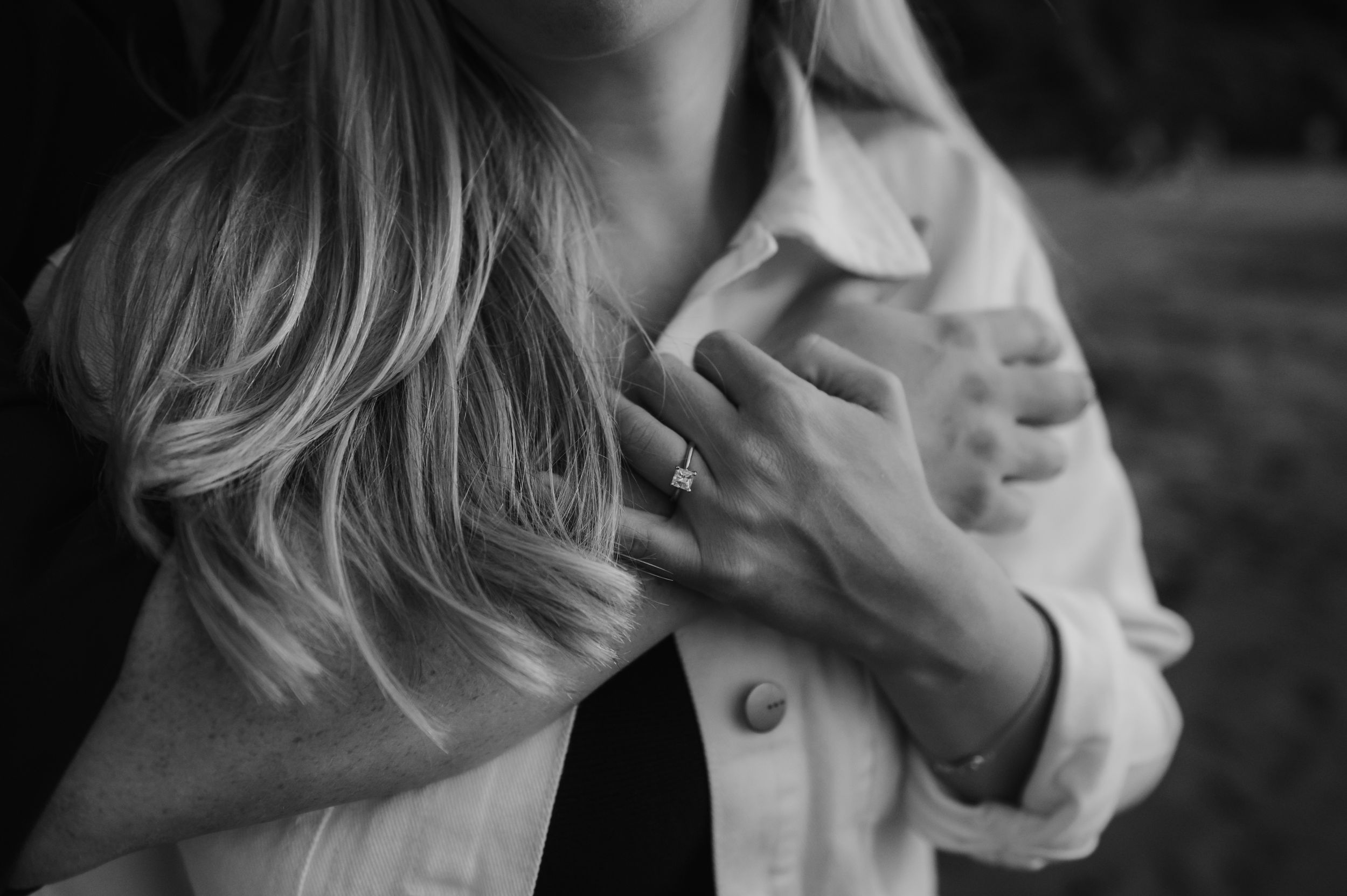 Black and white photo of someone in a white button-down shirt clutching their collar.
