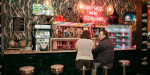Cozy bar interior with neon signs and hanging dollar bills covering the ceiling and walls.