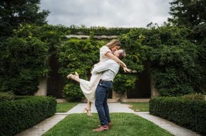 A romantic moment captured in a lush garden setting with manicured hedges and stone archway.