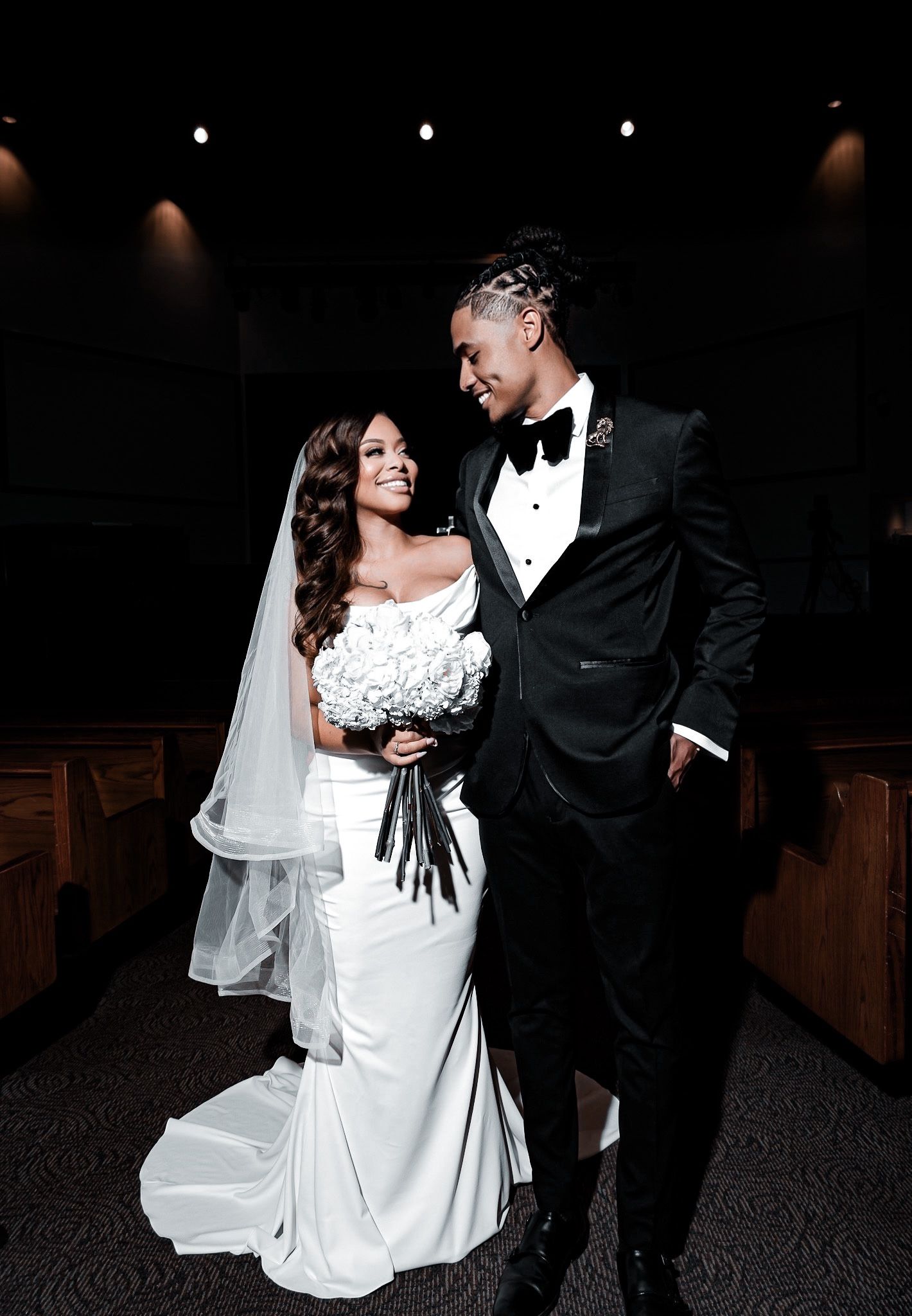 Wedding couple posing in elegant church with dark dramatic lighting.