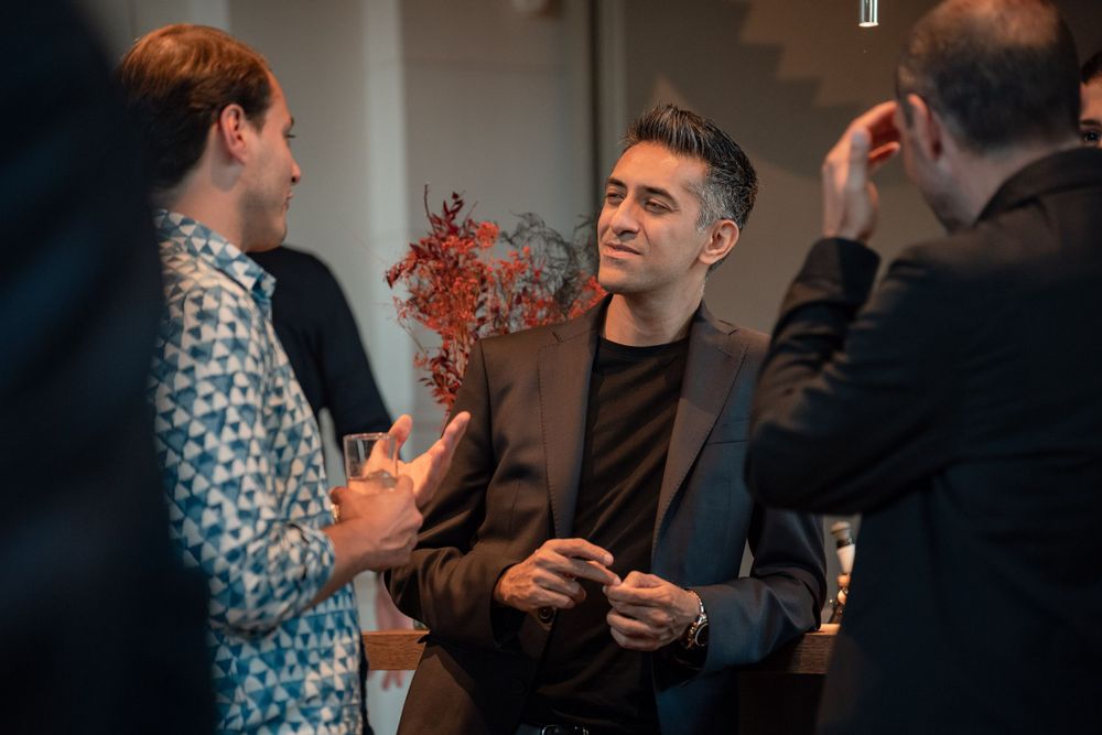 Group of people engaged in animated conversation at a networking event indoors.