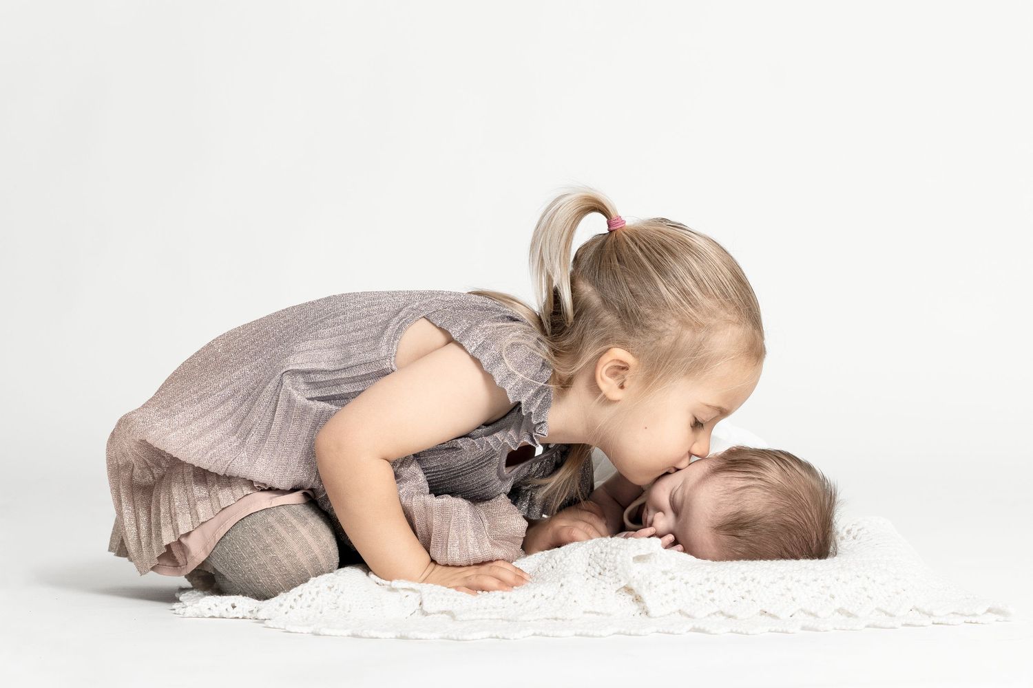 Storesøster giver lillebror et kærligt kys – søskendebillede fotograferet i studie af familie- og babyfotograf i Jægerspris, Frederikssund o