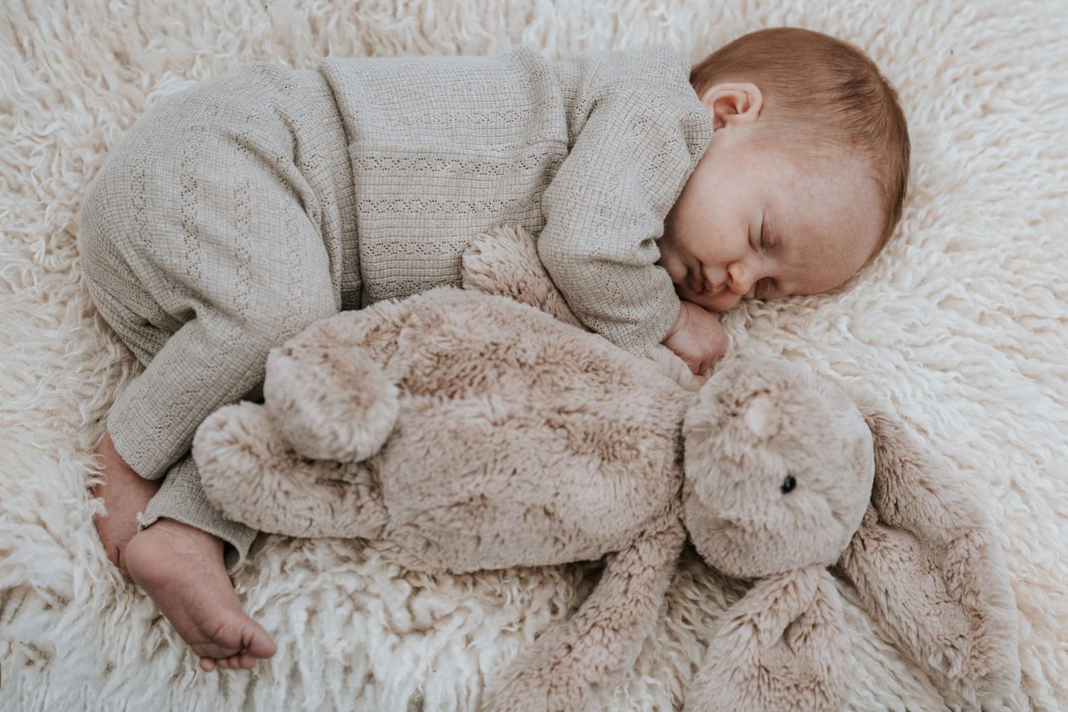 Nyfødt baby sover trygt med bamse – professionel babyfotografering i bløde, naturlige toner. Book en newborn session hos Chh_foto i dag