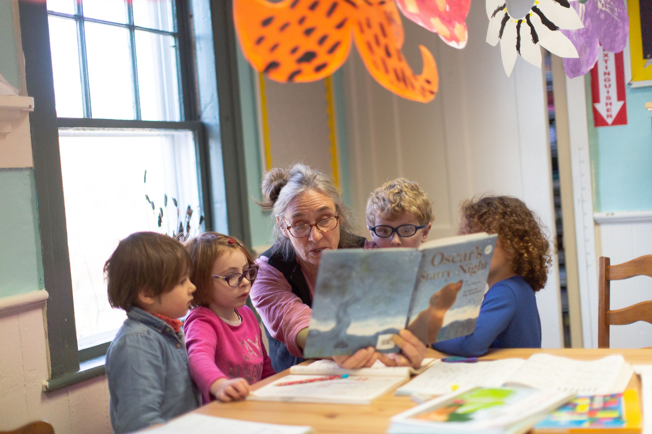 Colorful paper butterflies and decorations hang from the ceiling in a bright classroom.