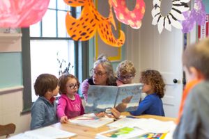 Students working at tables in a classroom decorated with orange and pink paper butterflies.