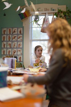 View across a classroom showing educational posters and student work displayed on green walls.