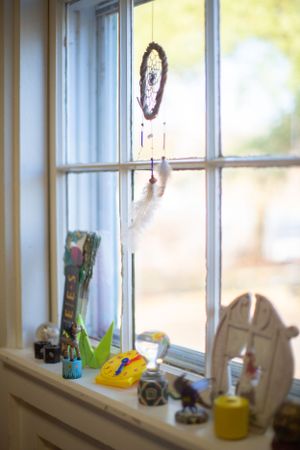 Sunlit classroom window with decorative items and supplies on the windowsill.
