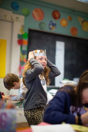 Students engaged in classroom activity with colorful decorations visible in background.