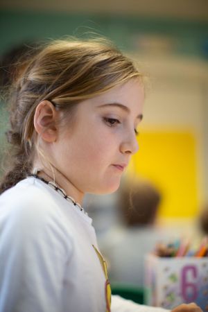 Side profile view of student in classroom with soft natural lighting.