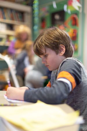Side view of students concentrating on their work at classroom tables.