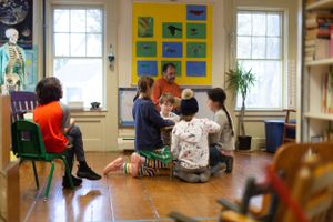 Wide angle view of a bright classroom with windows and student artwork on display.