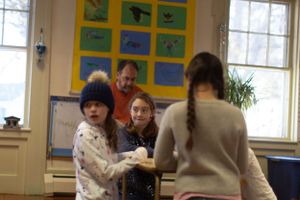 Group activity in a bright classroom with nature-themed artwork displayed on yellow wall.