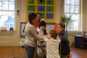 Small group engaged in educational activity beneath wall display of blue and green artwork.