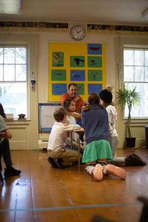 Students participate in group activity beneath colorful nature-themed wall display.