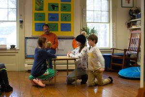 Children gather around for an interactive learning session on the wooden classroom floor.